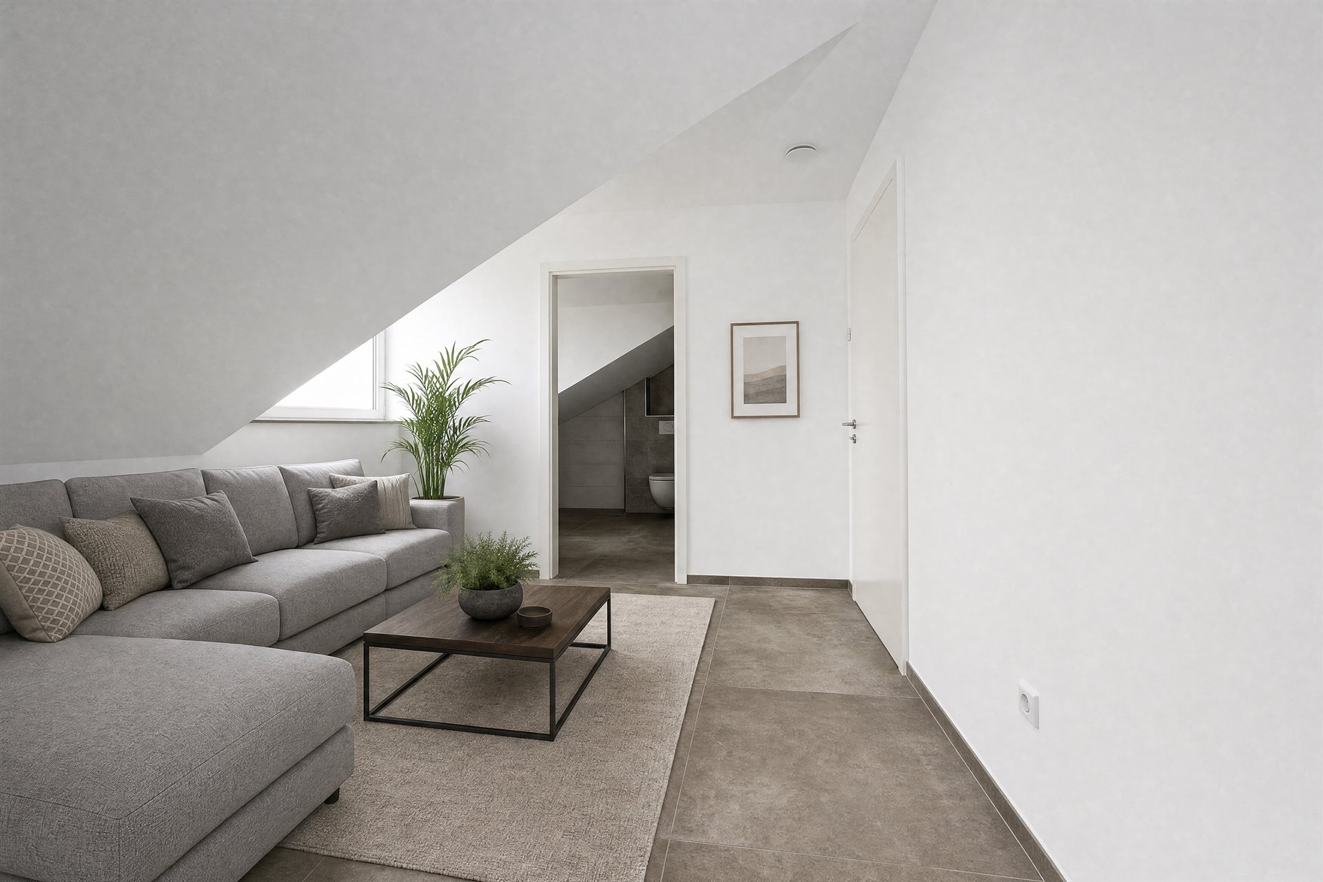 Top-floor loft living room under the mansard roof — large-format concrete-look tile floor, grey sectional sofa, palm plant, doorway to the bathroom visible