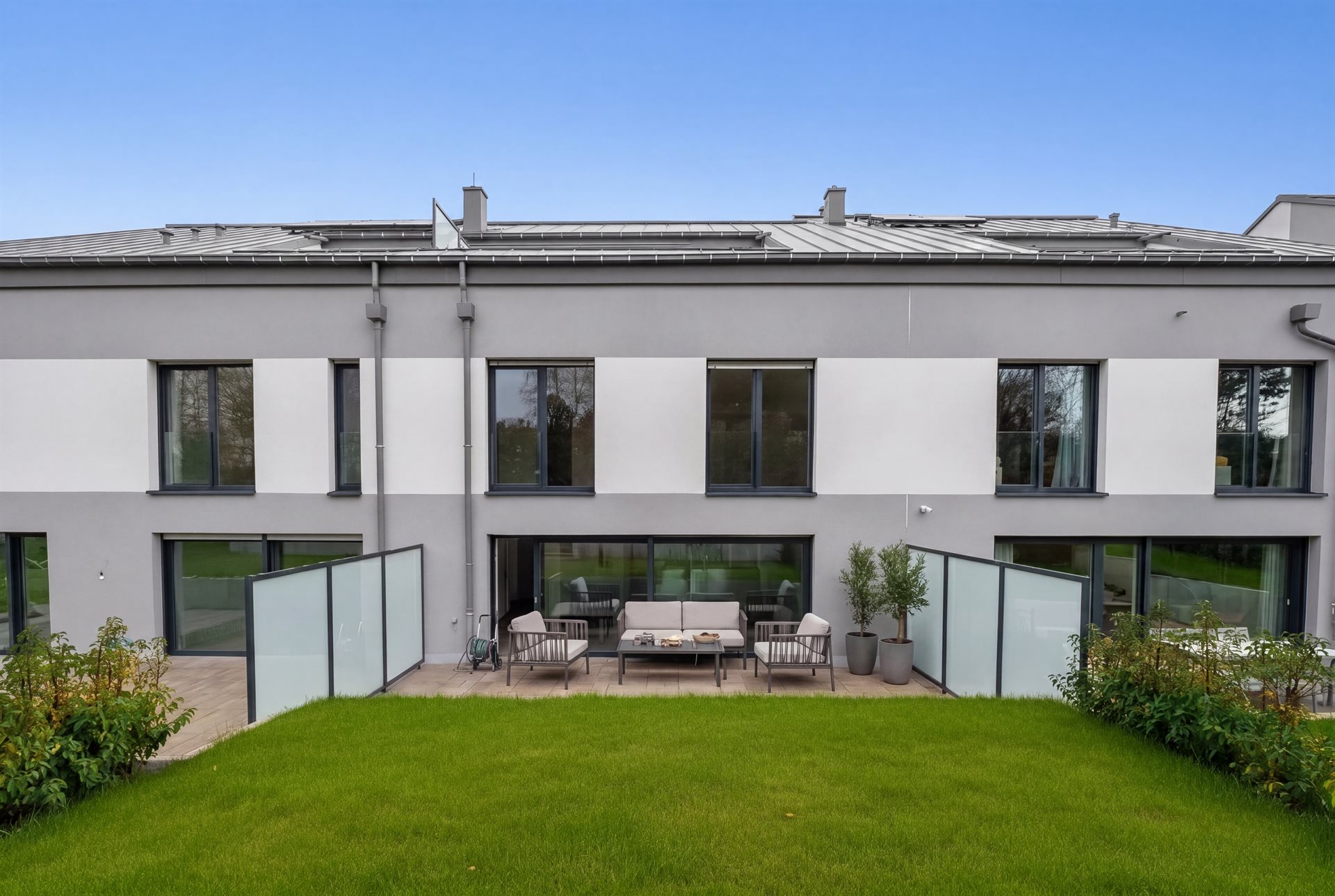 Rear facade and private garden — staged terrace with seating area and planters on a sunny day
